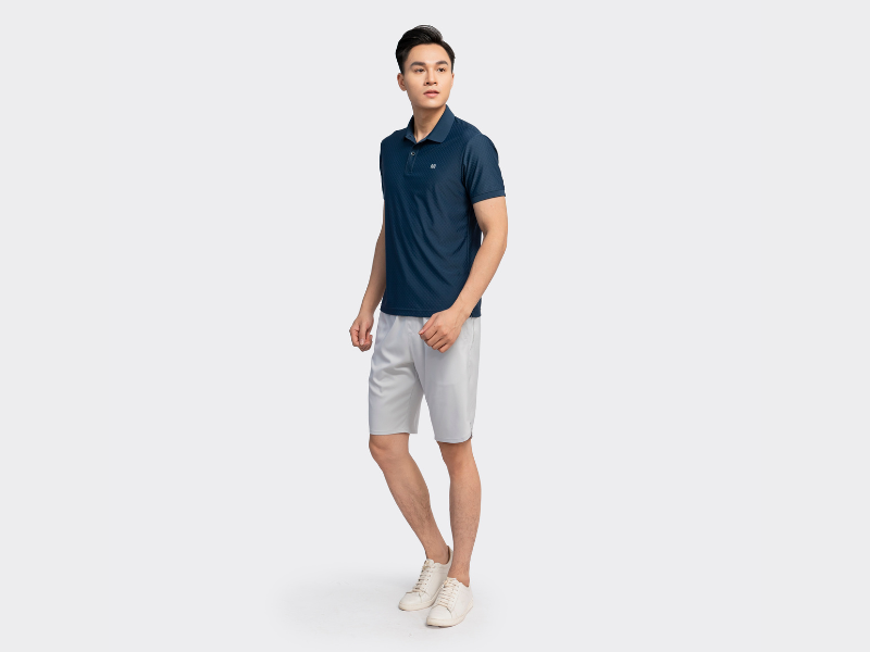 Một chàng trai đang tạo dáng với phong cách thời trang đường phố, mặc quần lửng qua đầu gối nam màu be, áo hoodie rộng rãi và giày thể thao. Anh ấy đứng trước một bức tường graffiti đầy màu sắc, thể hiện sự tự tin và cá tính mạnh mẽ, phù hợp với phong cách “sadboizaintcry”.
